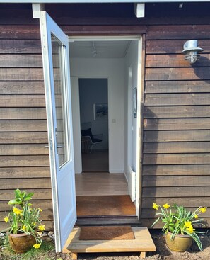 A wooden house with a door open, revealing an interior with a chair and a table.