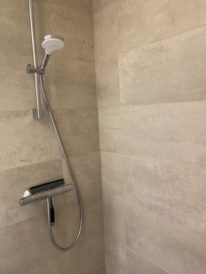 A shower with a handheld showerhead and a handheld hose.