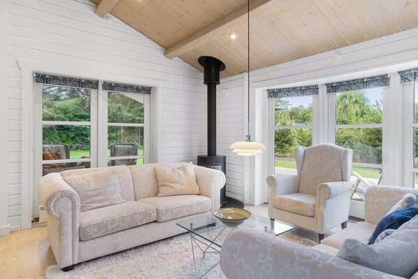 A cozy living room with a beige sofa, a chair, a glass coffee table, and a black fireplace.