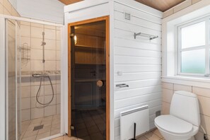 A bathroom with a shower, toilet, and a window.
