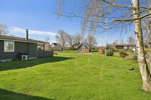 A residential area with houses, a grassy yard, and a swing set. - Lovely cottage within walking distance to the sea (Brenderup)