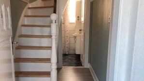 Una escalera que lleva a un baño con un lavabo blanco y una cortina de ducha.
