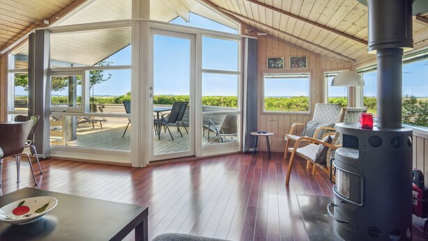 A covered patio with a wood stove, glass doors leading to an outdoor seating area, and a view of the outdoors. - Beach house with sea view of the Great Belt (Skælskør)