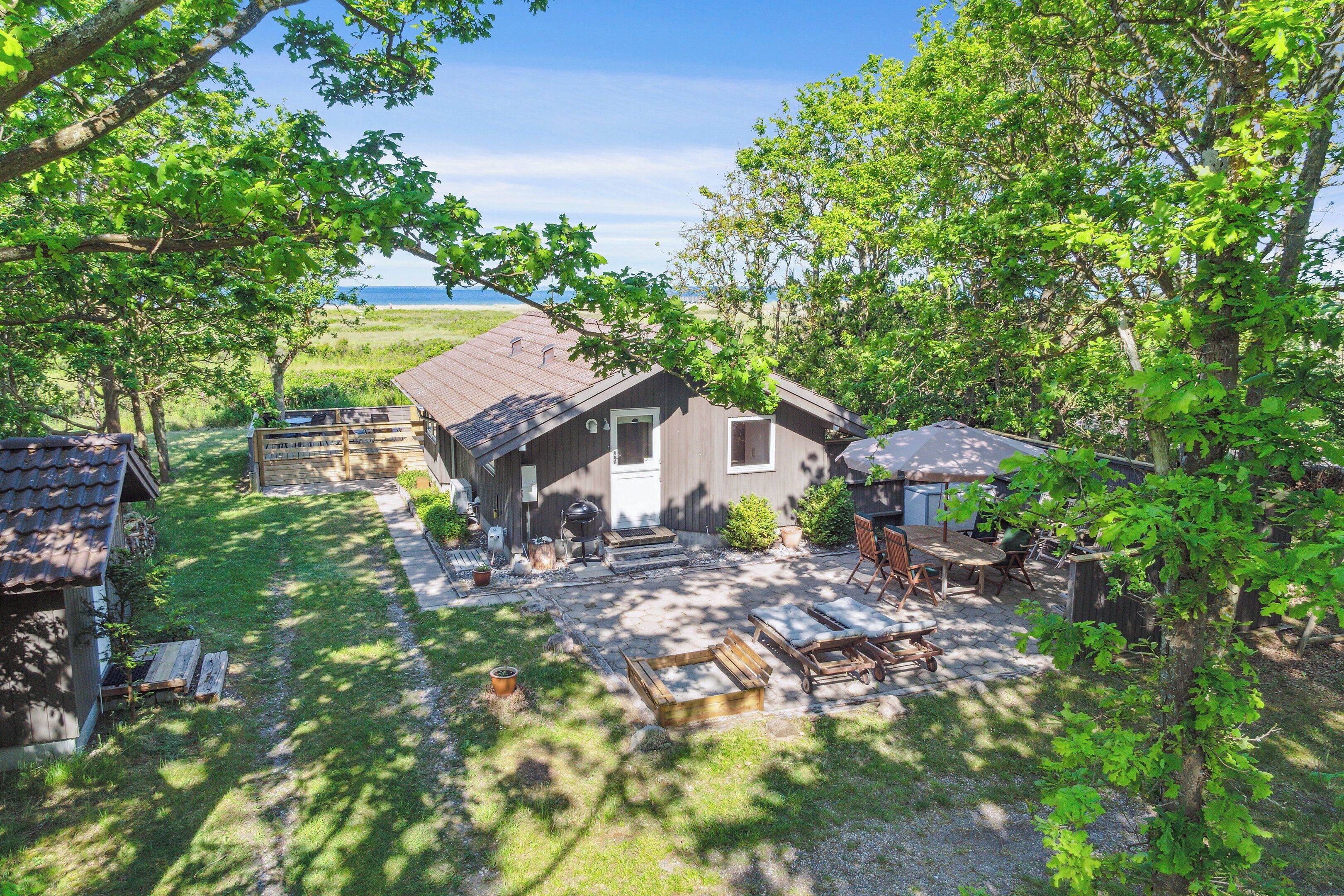 Un chalet rustique doté d’une terrasse, de mobilier d’extérieur et offrant une vue sur l’océan.