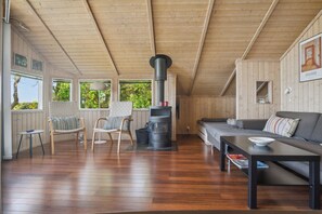 Un salon chaleureux avec un plafond en bois, un canapé, une table et une cheminée.