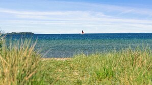 A coastal scene with a lighthouse in the distance, clear blue water, and grassy foreground. - Beach house with sea view of the Great Belt (Skælskør)