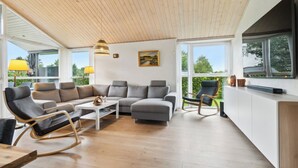 A modern living room with a sectional sofa, a rocking chair, and a coffee table. - Lovely holiday home Spa/sauna, carcharger, river (Fårvang)