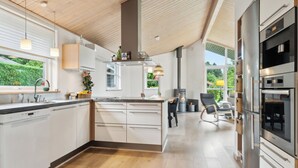 A modern kitchen with a central island, built-in appliances, and a view of the outdoors. - Lovely holiday home Spa/sauna, carcharger, river (Fårvang)