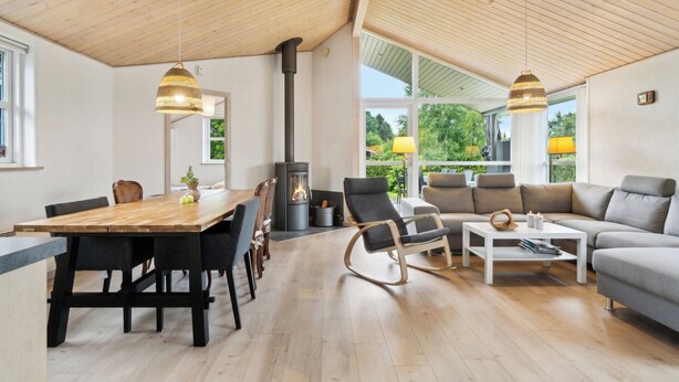 A modern interior with a wooden dining table, black chairs, a sofa, and a white coffee table. - Lovely holiday home Spa/sauna, carcharger, river (Fårvang)