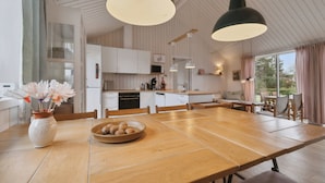 Een moderne keuken met houten kastjes, een eettafel en hanglampen.