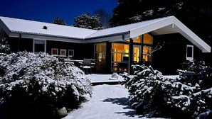 Une maison moderne avec une allée enneigée et une entrée bien éclairée.