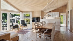 Un espace de vie à aire ouverte comprenant une table à manger, des chaises, un téléviseur et un coin cuisine.