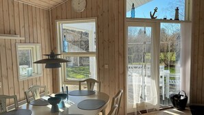 Ein Zimmer mit Holzwänden, einem Esstisch, Stühlen, einer Uhr und großen Fenstern.