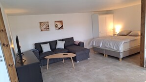 A modern room with a sofa, a small round table, a bed, and a TV.