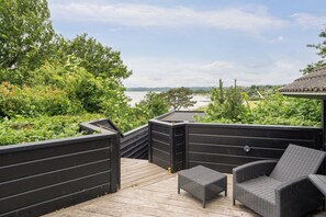 Eine Terrasse mit Korbmöbeln und Blick auf ein Gewässer.