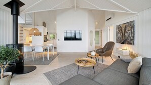 Een ruime woonkamer met een open haard, zitplaatsen en een groot schilderij.