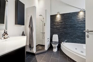 Een moderne badkamer met een witte wastafel, toilet, douche en bad.