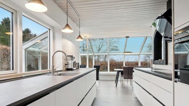 A modern kitchen with large windows, a dining area, and a view of the outdoors.
