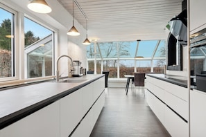 Een moderne keuken met grote ramen, een eethoek en uitzicht op de omgeving.