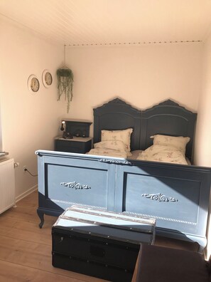 Een slaapkamer met een donkerblauwe bed, twee nachtkastjes, een hangplant en een kledingkast.