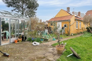 A garden with a greenhouse, potted plants, and a small tree. - Lovely holiday apartment in Rønne (Rønne)
