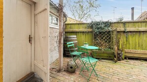 Eine Terrasse mit Tisch und Stühlen, einem Holzzaun und einer Tür.