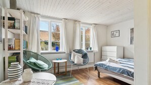 Ein Schlafzimmer mit einem Bett, einem Sessel, einem Tisch und einem Bücherregal.