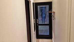 Un pasillo estrecho con una puerta que da a una habitación con vista a un bosque.