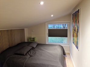 A bedroom with a bed, a window, a green nightstand, and a wall-mounted artwork. - Quiet area 15 km to the beach (Skibby)