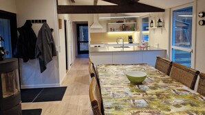 Una cocina moderna con una isla central, vigas de madera en el techo y un comedor con mantel estampado.