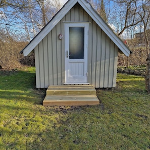 A small wooden shed with a white door and a small porch. - Quiet area 15 km to the beach (Skibby)