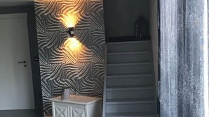 A modern interior with a zebra-patterned wall, a staircase, and a white console table. - Maison de Vacance a 10 min du Circuit de spa Francorchamps et 5min de Spa (jalhay)