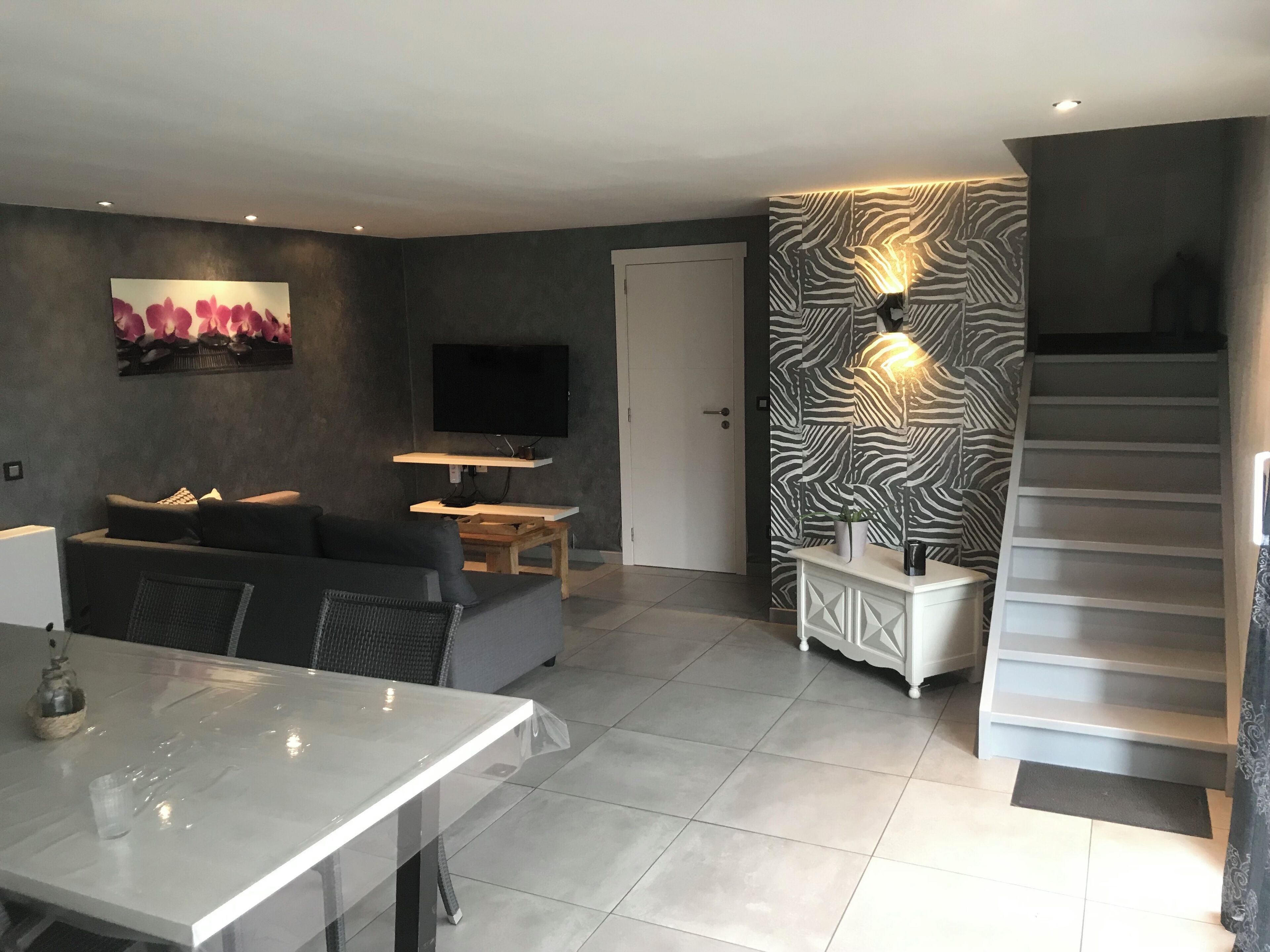 Un salon moderne avec un canapé, un téléviseur et un escalier.