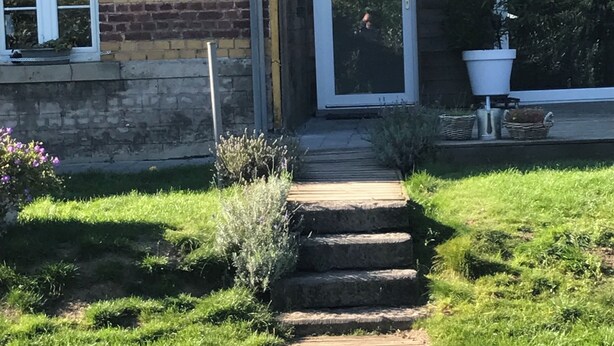 A wooden pathway leading to a house with a brick exterior and a white door. - Maison de Vacance a 10 min du Circuit de spa Francorchamps et 5min de Spa (jalhay)