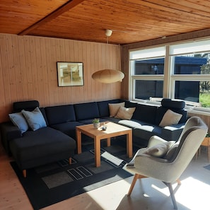 A modern living room with a sectional sofa, a coffee table, a chair, and a hanging light fixture.