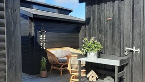 Eine Holzterrasse mit einem Korbstuhl und einem kleinen Tisch mit einem Blumentopf.