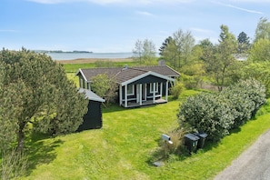 Een huis met een groot gazon, een brievenbus en uitzicht op een meer.