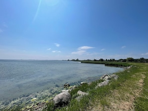 A clear view of a calm lake with a grassy shoreline and rocks.