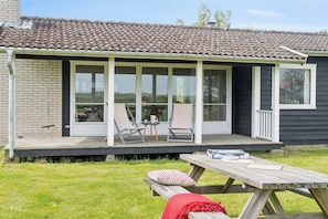 Ein Haus mit überdachter Veranda, einem Holztisch und zwei Stühlen.