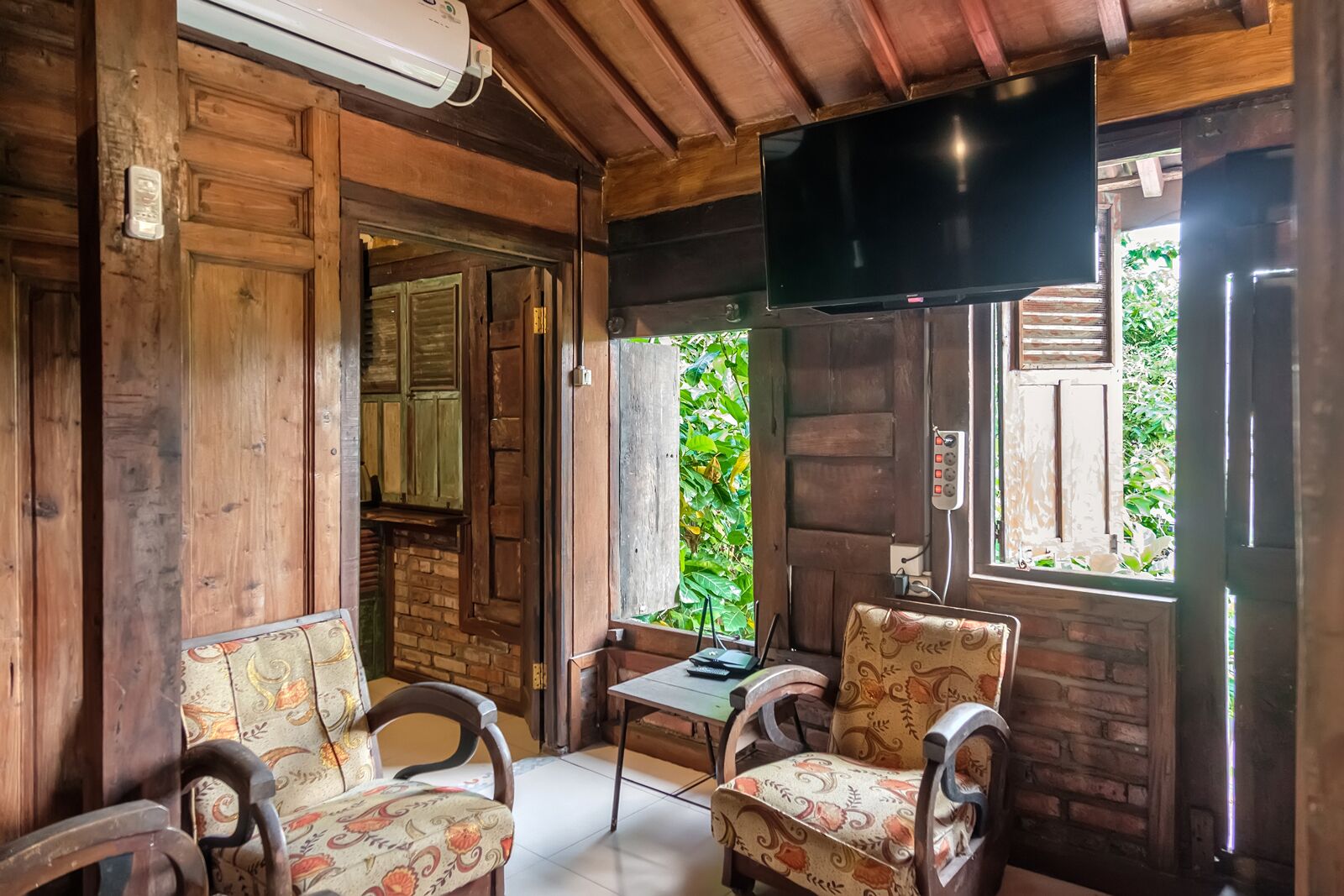 Un interior de madera con dos sillones tapizados, una mesita y un televisor de pared.