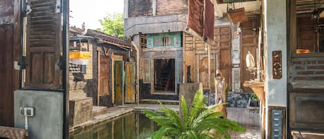 A traditional courtyard with a central water feature, wooden doors, and a hanging lantern.