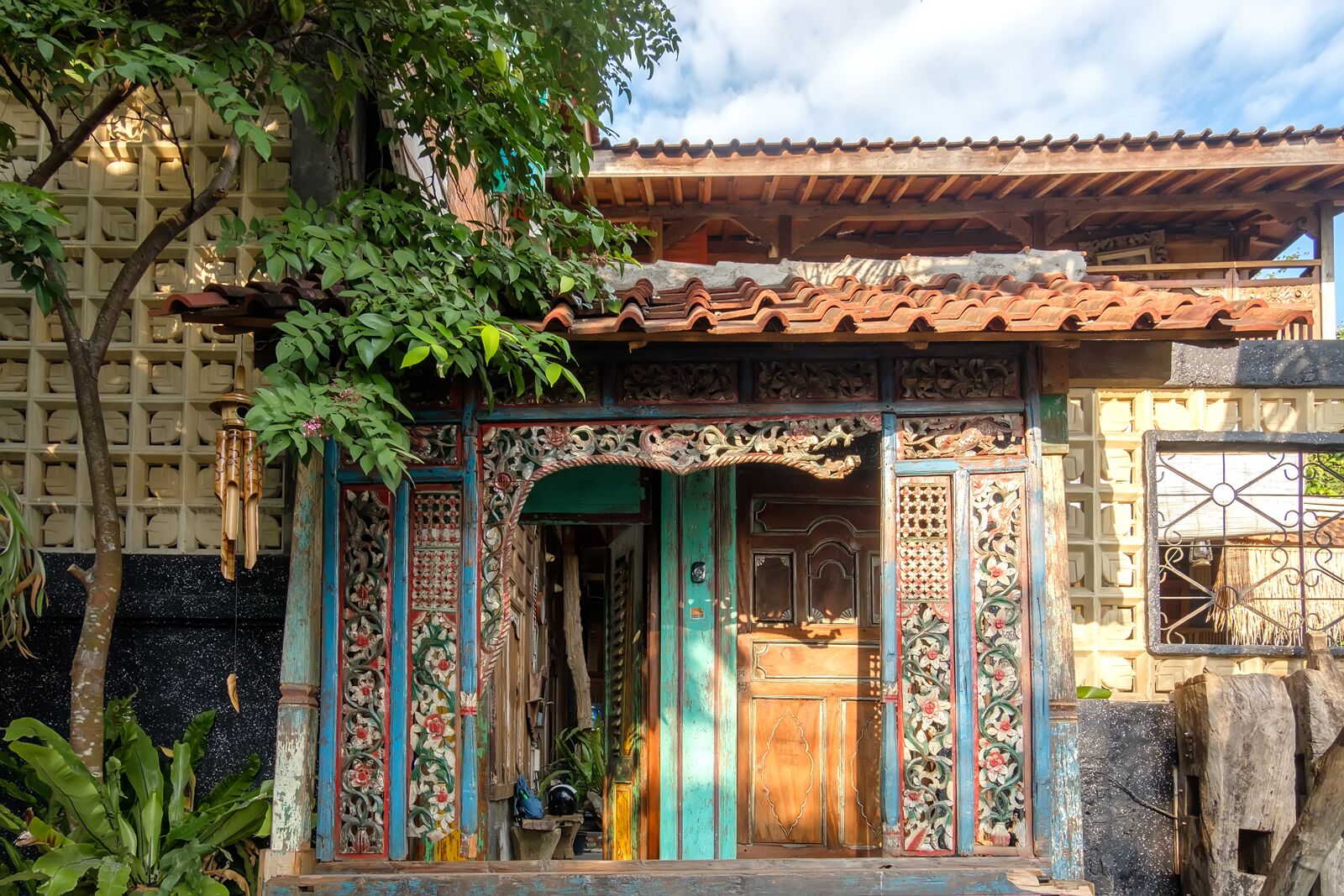 A traditional building with a tiled roof, ornate wooden doors, and a lattice wall.
