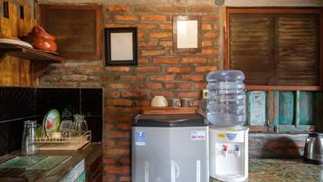 A kitchen with a brick wall, a refrigerator, a water dispenser, and a sink.