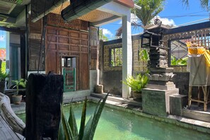 Un patio tradicional con piscina, estructuras de madera y plantas en macetas.