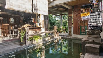 Un área de piscina con terraza de madera, plantas en macetas y un espacio de estar al aire libre de estilo rústico.