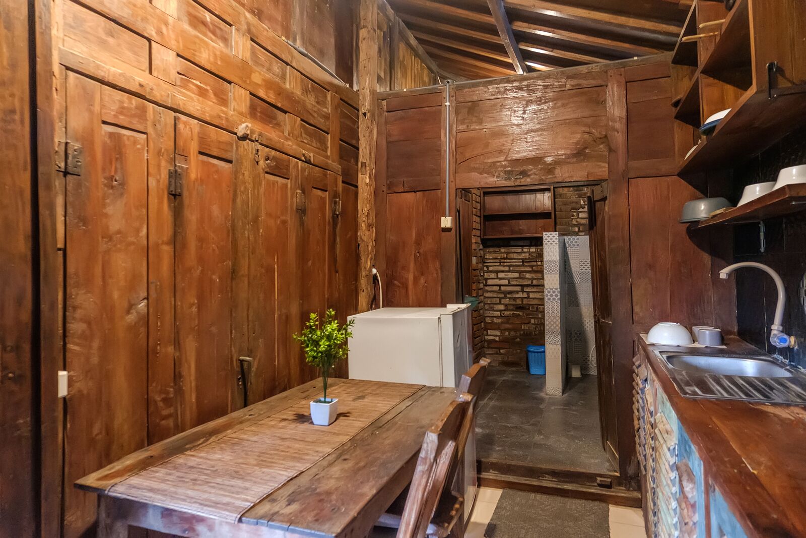 Une cuisine rustique en bois, avec une table en bois, un réfrigérateur blanc et un évier.