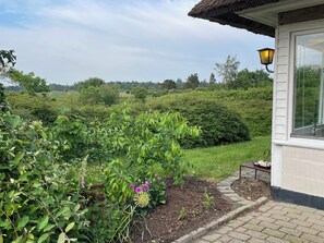 Une maison avec un jardin, un banc et un lampadaire.