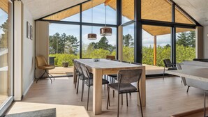 A spacious dining area with a long table, multiple chairs, and pendant lights. - Impressive holiday cottage, by the Helsnæs Bay! (Millinge)
