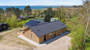 A wooden cabin with a gravel driveway, solar panels, and a view of the sea. - Impressive holiday cottage, by the Helsnæs Bay! (Millinge)