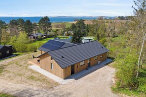A wooden cabin with a gravel driveway, solar panels, and a view of the sea. - Impressive holiday cottage by the Helsnæs Bay (Millinge)